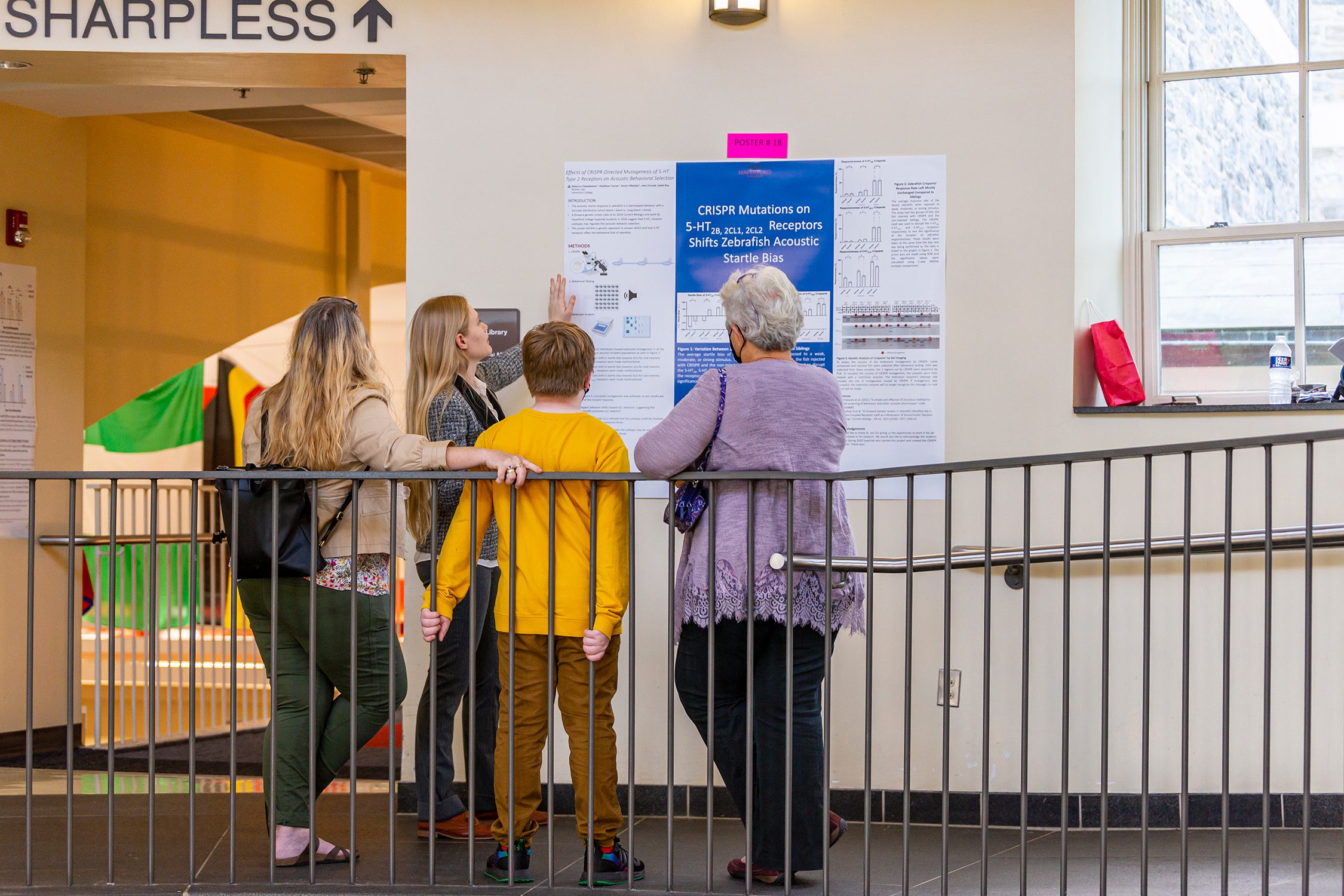 Three attendees listen to a poster presentation. examine and discuss a poster at the Undergraduate Science Research Symposium. Photo by Patrick Montero.