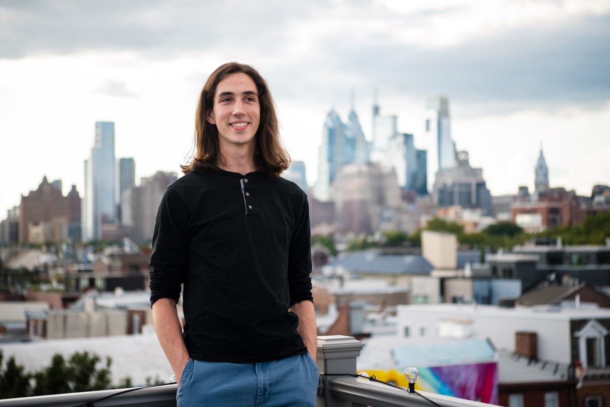 Adrian Velonis '22 stands on a rooftop in front of the Philadelphia skyline. Photo by Holden Blanco '17.