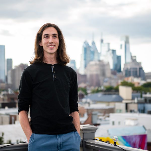 Adrian Velonis '22 stands on a rooftop in front of the Philadelphia skyline. Photo by Holden Blanco '17.