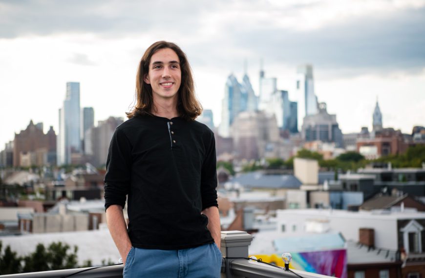 Adrian Velonis '22 stands on a rooftop in front of the Philadelphia skyline. Photo by Holden Blanco '17.