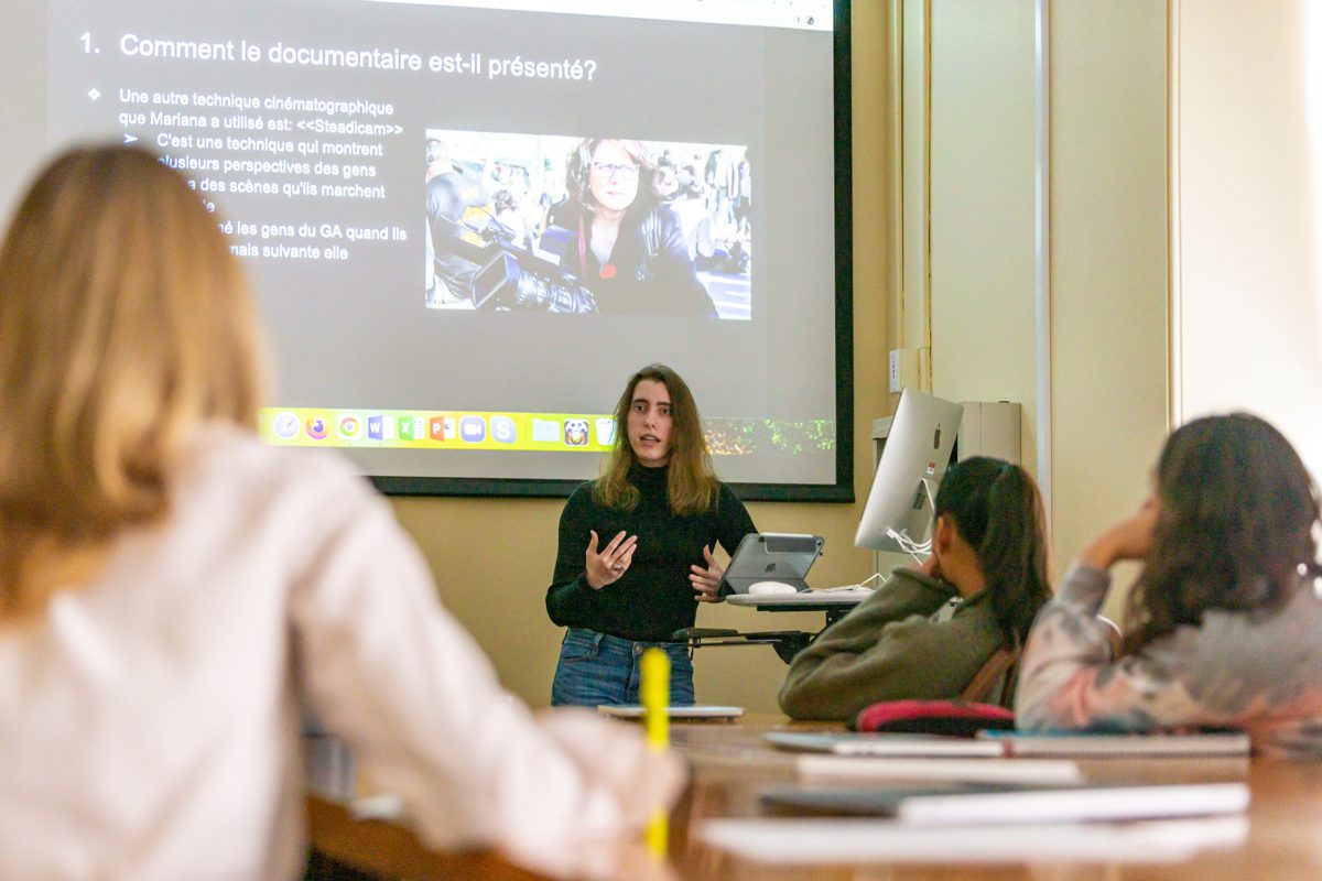 Kate stands in front of the class under a projection that reads "Comment le documentaire est-il présenté?"