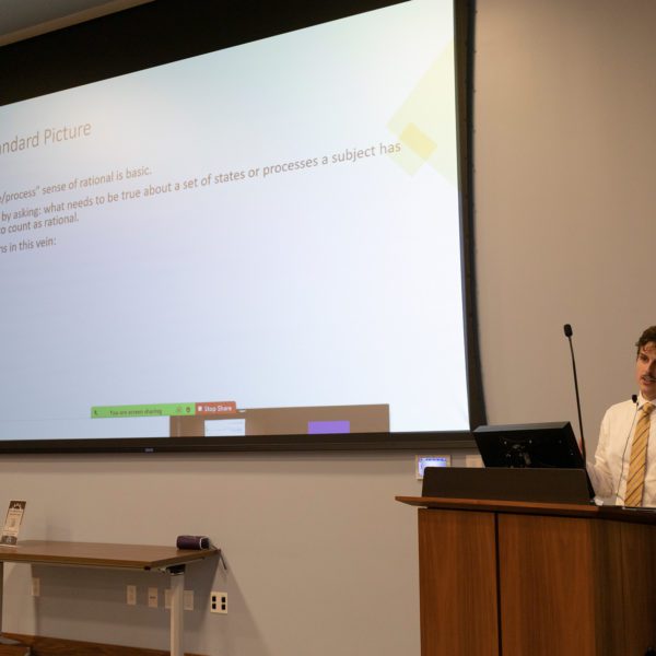 Zach Gabor '15 stands behind a podium during his presentation on philosophy in Lutnick Library. Photo by Sabine Mejia '25.