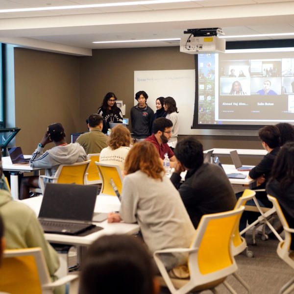 Students stand at the front of the room presenting a project as part of the Tri-Co Hackathon. Photo by Anna Braun '26.