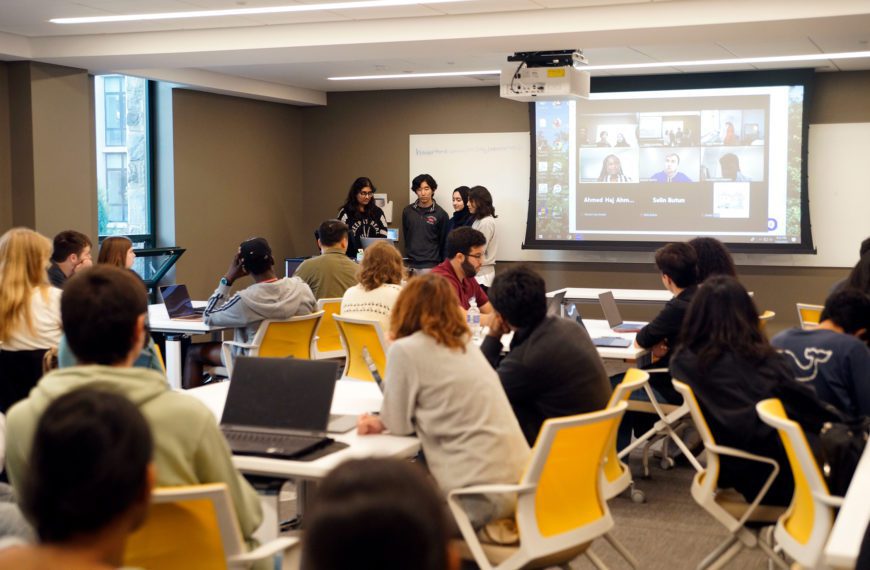 Students stand at the front of the room presenting a project as part of the Tri-Co Hackathon. Photo by Anna Braun '26.