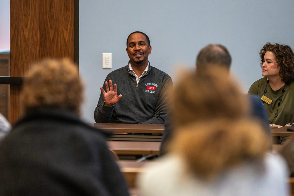 John McKnight smiles and holds up his hand while speaking.
