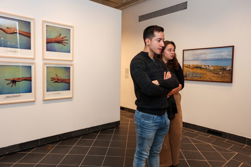 Two people look at the photographs, including four photos of hands in different positions.