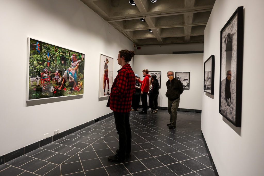 People walking through the gallery in front of photographs.
