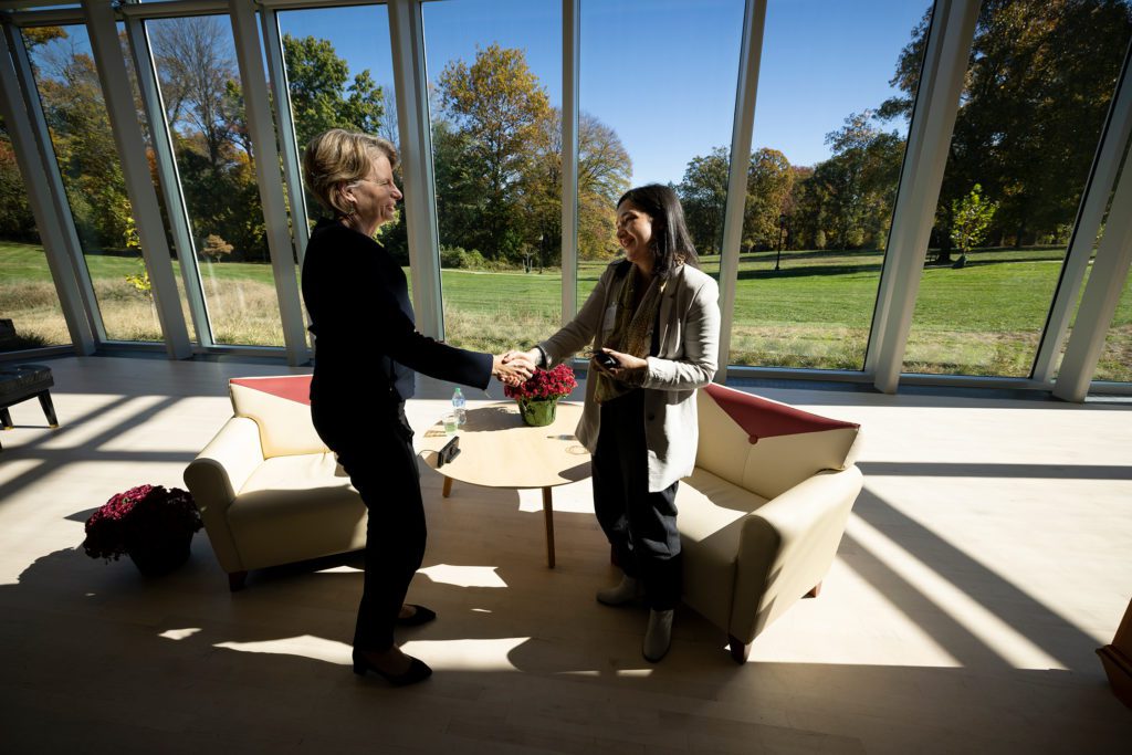 President Raymond and Ava Shirazi shake hands surrounded by the floor-to-ceiling windows of the concert hall.