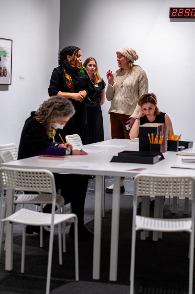 Attendees writing and reading at the white table. Photo by Logan de Raspide Ross '23.