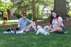 two people sitting on Founder's green with two small dogs