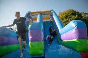 Two students coming down slide on inflatable obstacle course_photo by Holden Blanco '17