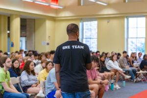 Speaker infront of students wearing a shirt that says "One Team" _photo by Patrick Montero