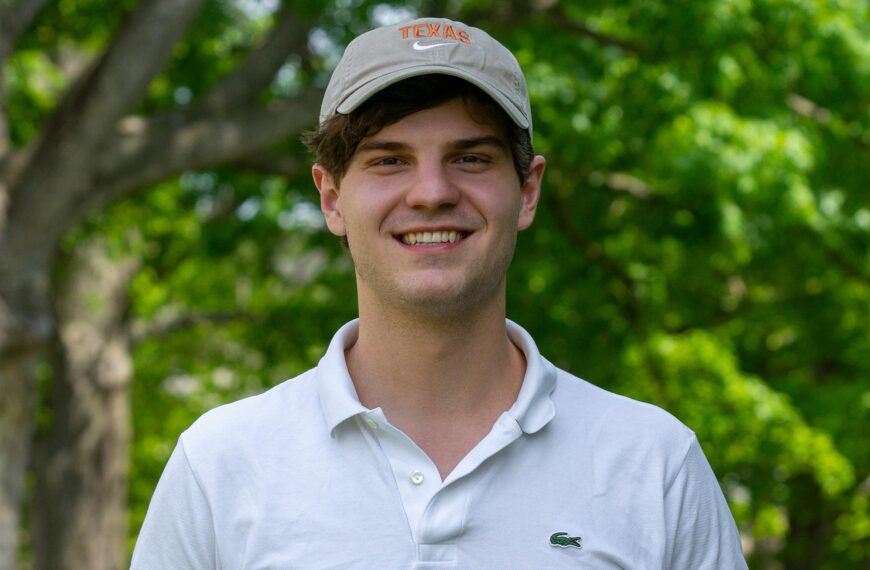 Filip Kesicki, wearing a white shirt and grey cap, stands against and out-of-focus arboretum bacground
