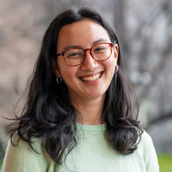In a portrait, Elena Bien wears glasses and a light green sweater.