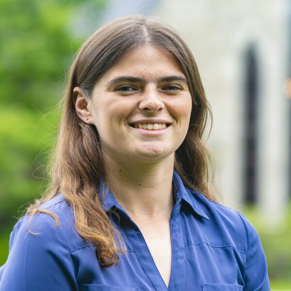 Theresa Haupt is pictured in a portrait on Haverford's campus. Lutnick Library is visible but out of focus behind her.