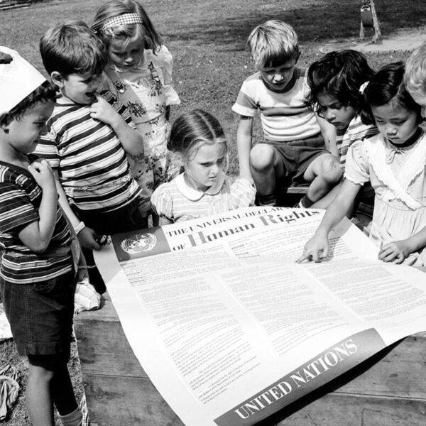 Eight children gather around a large printed copy of the U.N.'s Universal Declaration of Human Rights.