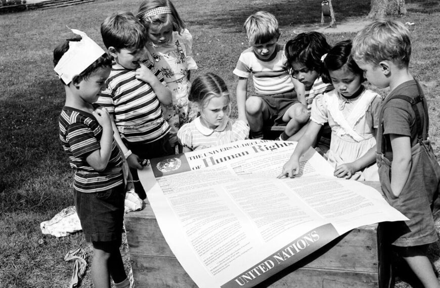 Eight children gather around a large printed copy of the U.N.'s Universal Declaration of Human Rights.